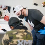 Brian Hackel, right, an overdose prevention specialist, helps Steven Baez, a client suffering addiction, find a vein to inject intravenous drugs at an overdose prevention center, OnPoint NYC, in New York, Feb. 18, 2022.