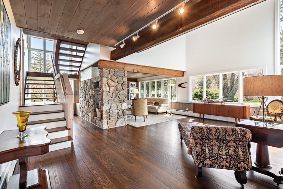 Living room with vaulted ceilings, hardwood floors, and picture windows facing the backyard.