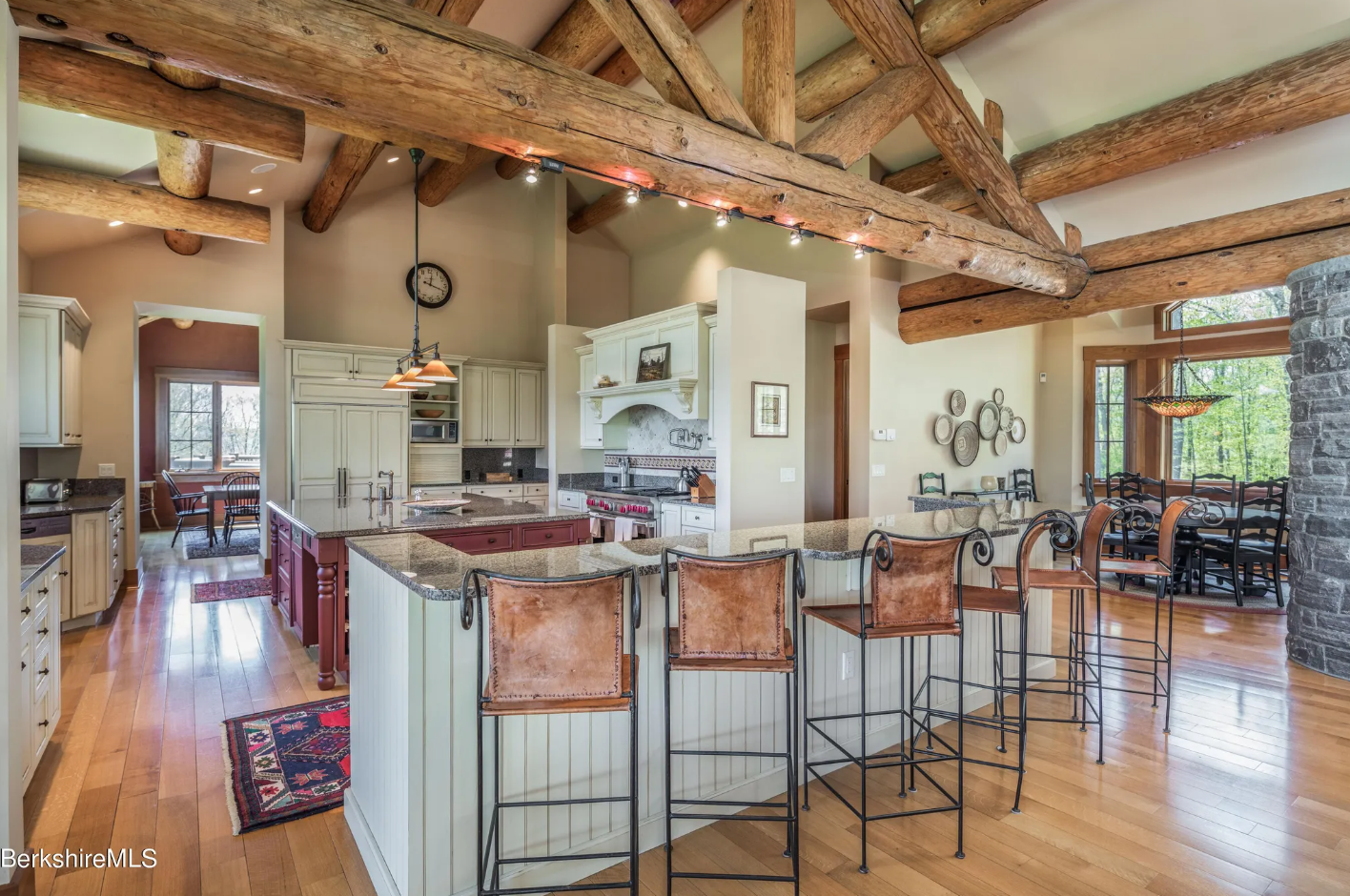 Kitchen with cream-colored beaded cabinetry, vaulted ceilings with exposed wood beams, a breakfast bar with seating for six, and stainless steel appliances.