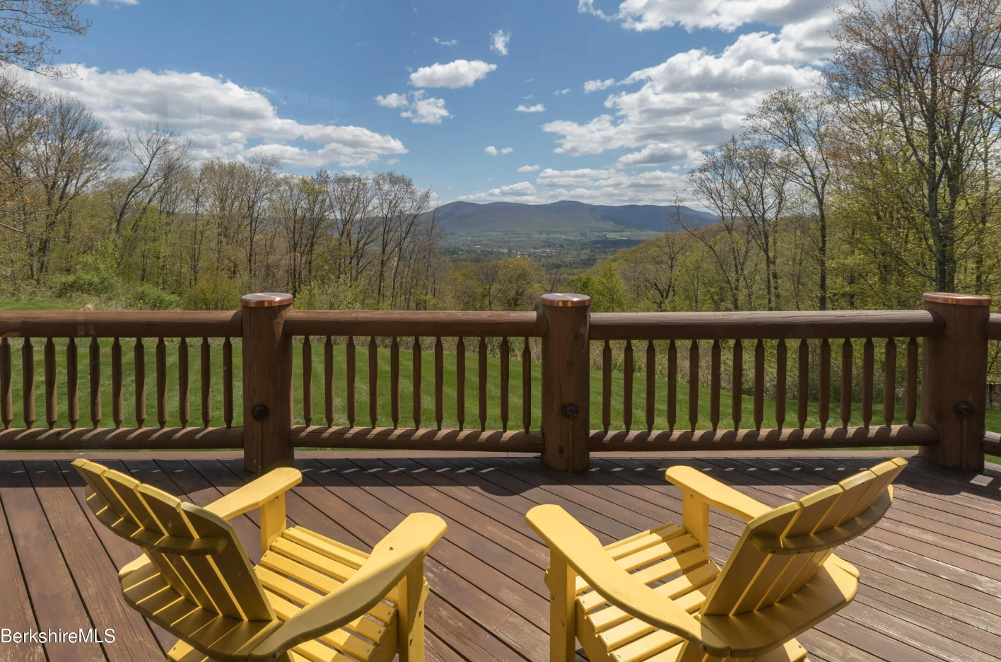 Yellow Adirondack chairs on a deck overlooking the mountains.