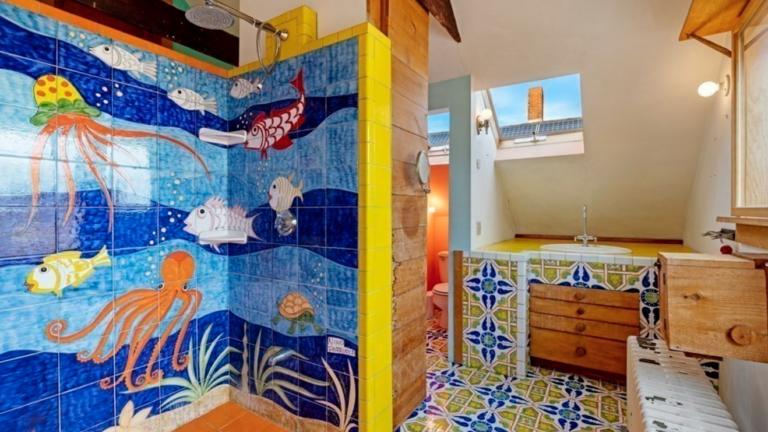This bathroom of this Gloucester home has yellow and blue floor tiling and a walk-in shower with an under-the-sea scene.