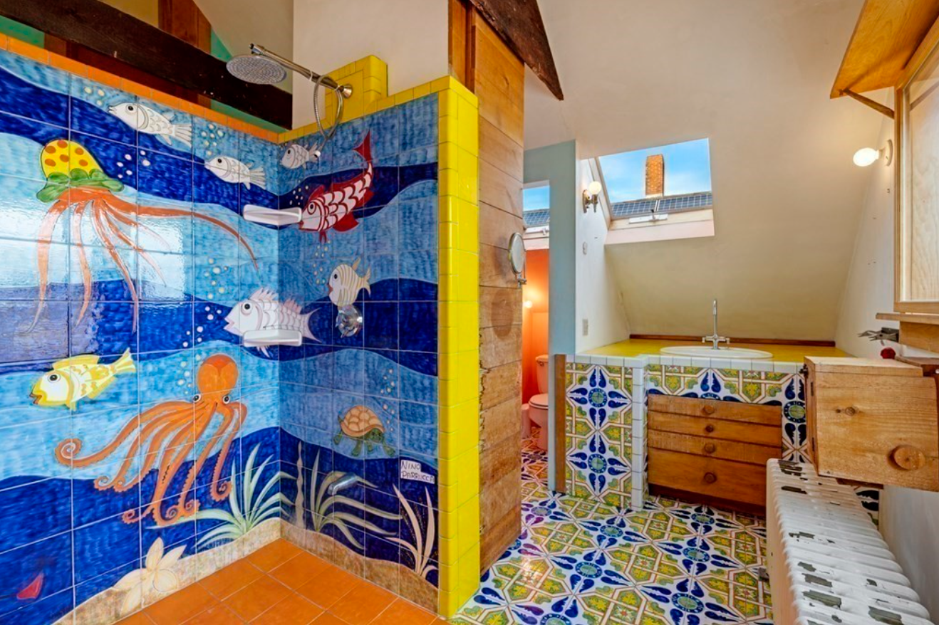 This bathroom of this Gloucester home has yellow and blue floor tiling and a walk-in shower with an under-the-sea scene.