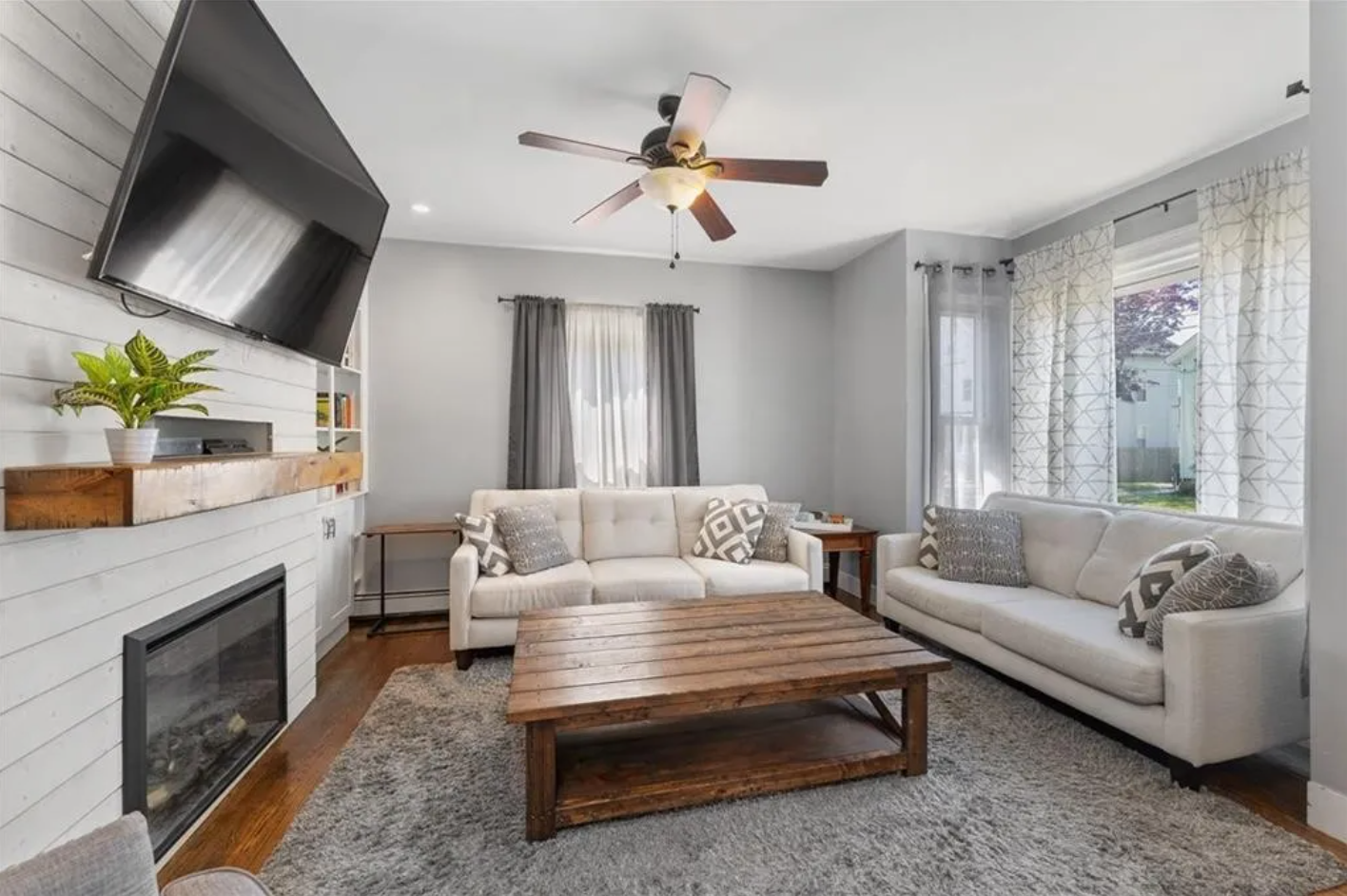 Living room with light gray walls, single-hung windows, hardwood floors, and fireplace.