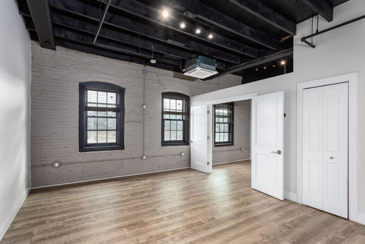 Living room with grey exposed brick accent wall and single-hung windows with muntins.