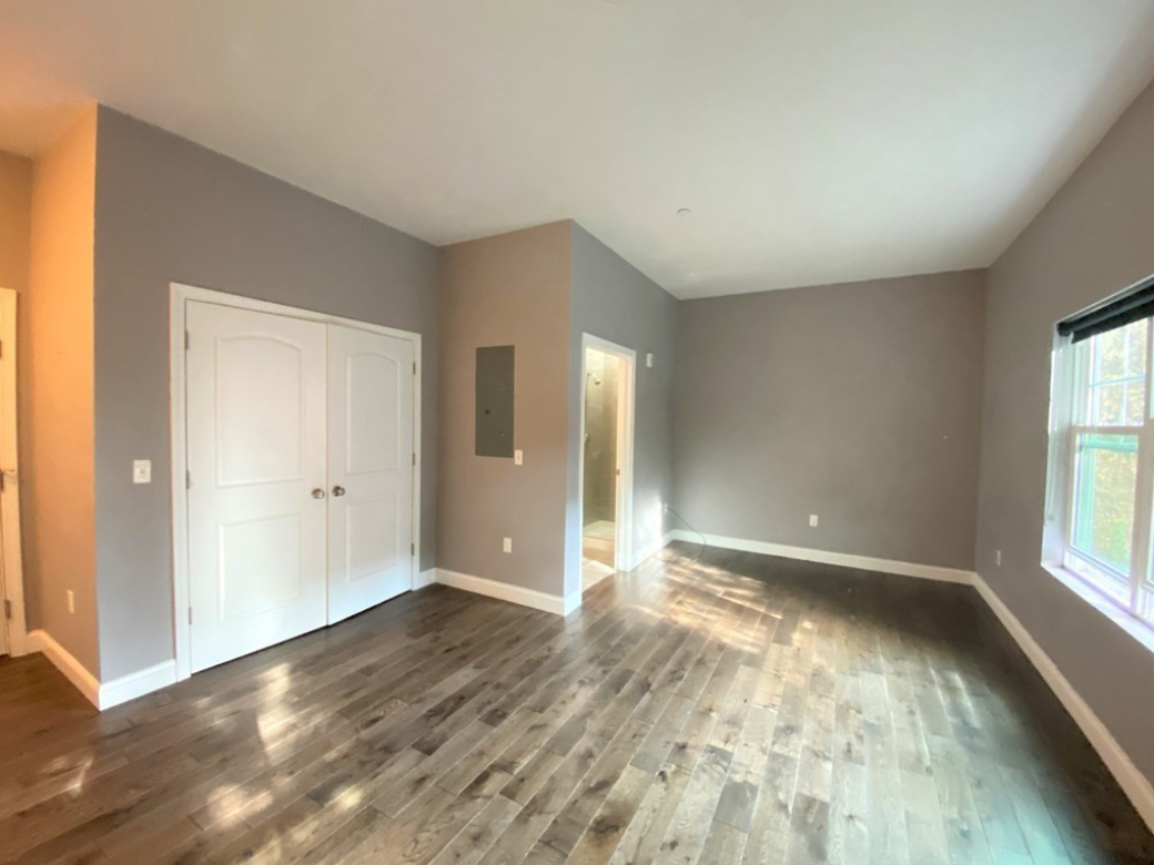 Living area with hardwood floors, grey walls, white trim, and single-hung windows.