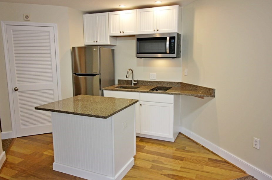 Kitchen with white shaker-style cabinetry, stainless steel appliances, and hardwood floors.