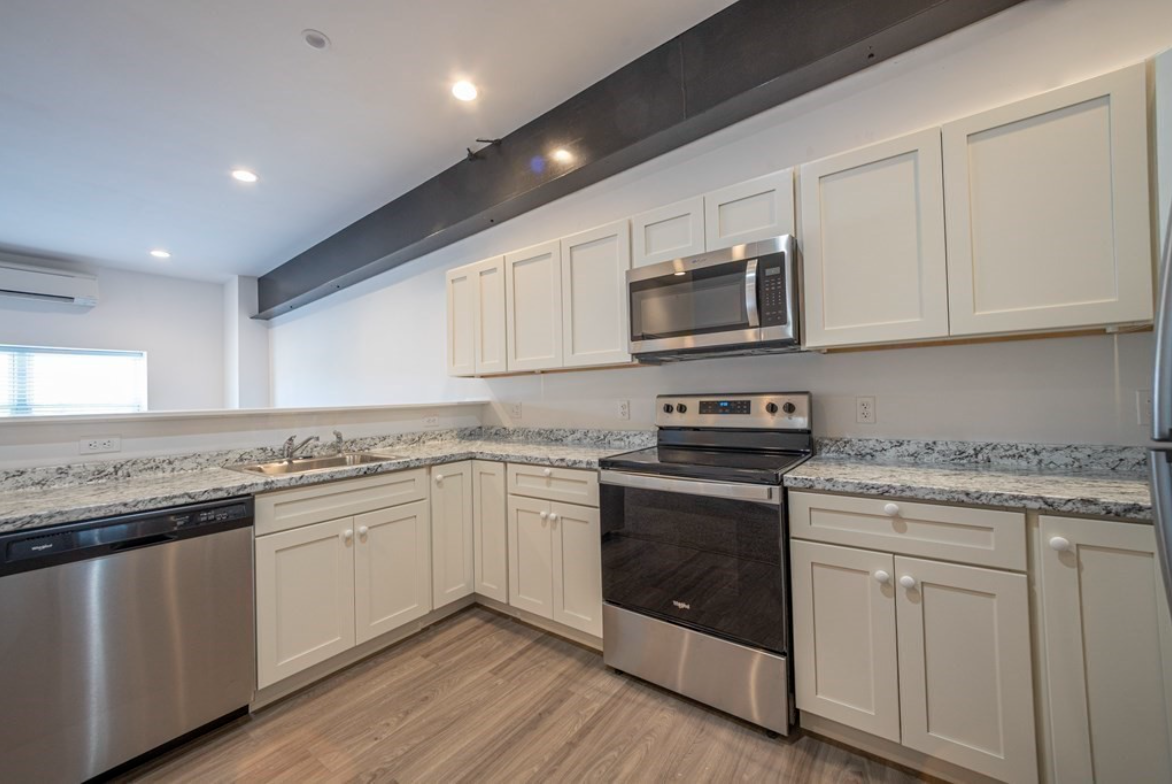 Kitchen with white Shaker-style cabinets, hardwood floors, and stainless steel appliances.