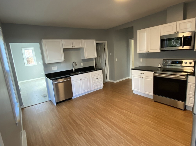 Kitchen with white Shaker-style cabinets, stainless steel appliances, and hardwood floors.