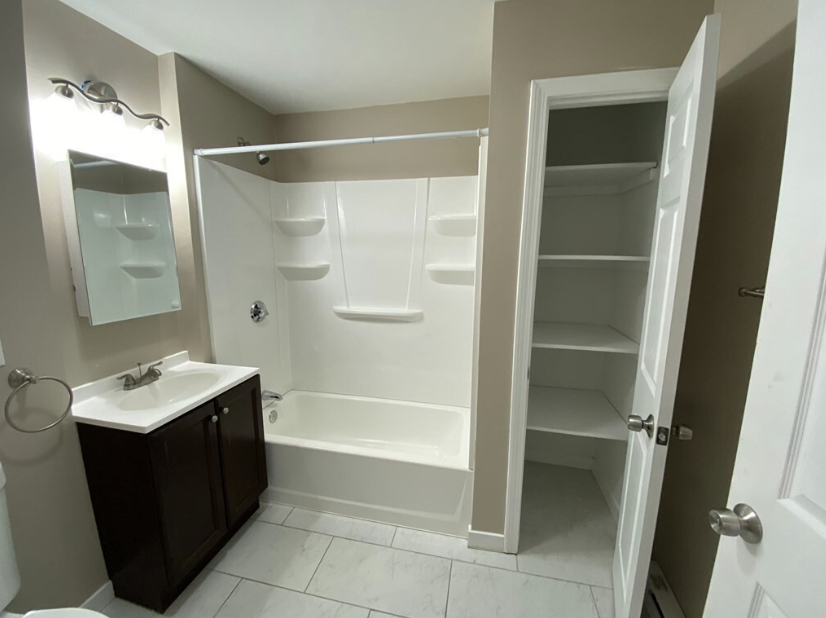 Bathroom with beige walls, single vanity, and combination shower-bathtub. 