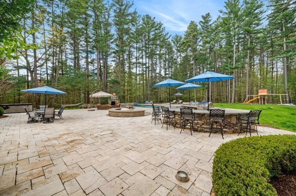 Patio with outdoor seating, brick oven, grill, and blue umbrellas.