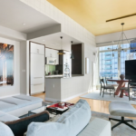 Living area with floor-to-ceiling windows, yellow ceiling and beige walls, and hardwood floors.