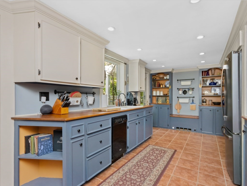 Kitchen with light blue beaded cabinets and built-in shelving. A window above the sink provides natural light.