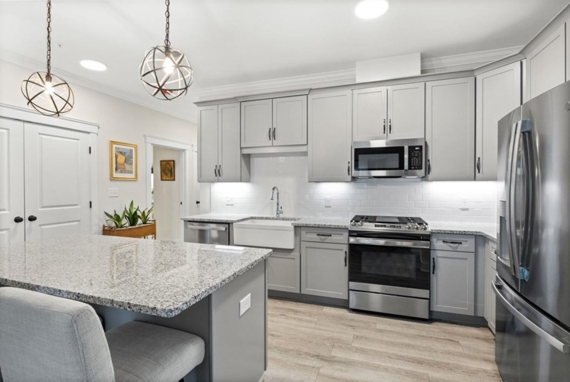 Kitchen with light gray Shaker-style cabinets, hardwood floors, stainless steel appliances, and pendant lighting.