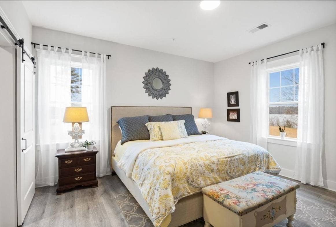 Bedroom with light gray walls, hardwood floors, and single-hung windows.