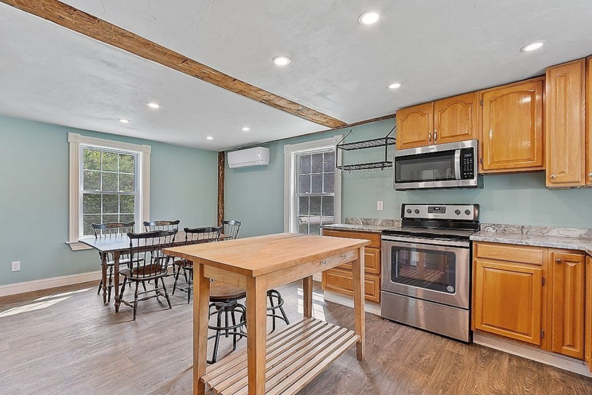 Kitchen with teal walls, wooden cabinets, hardwood floors, and stainless steel appliances.