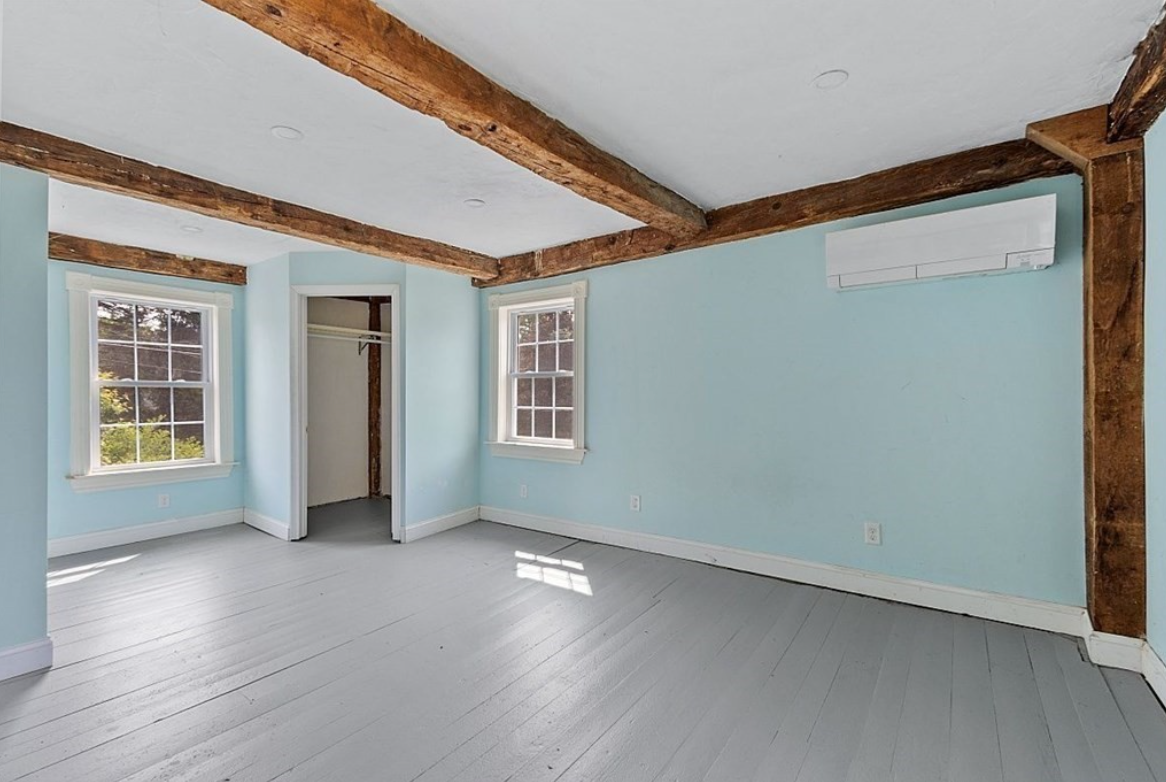 Room with light blue walls and exposed wood ceiling beams.