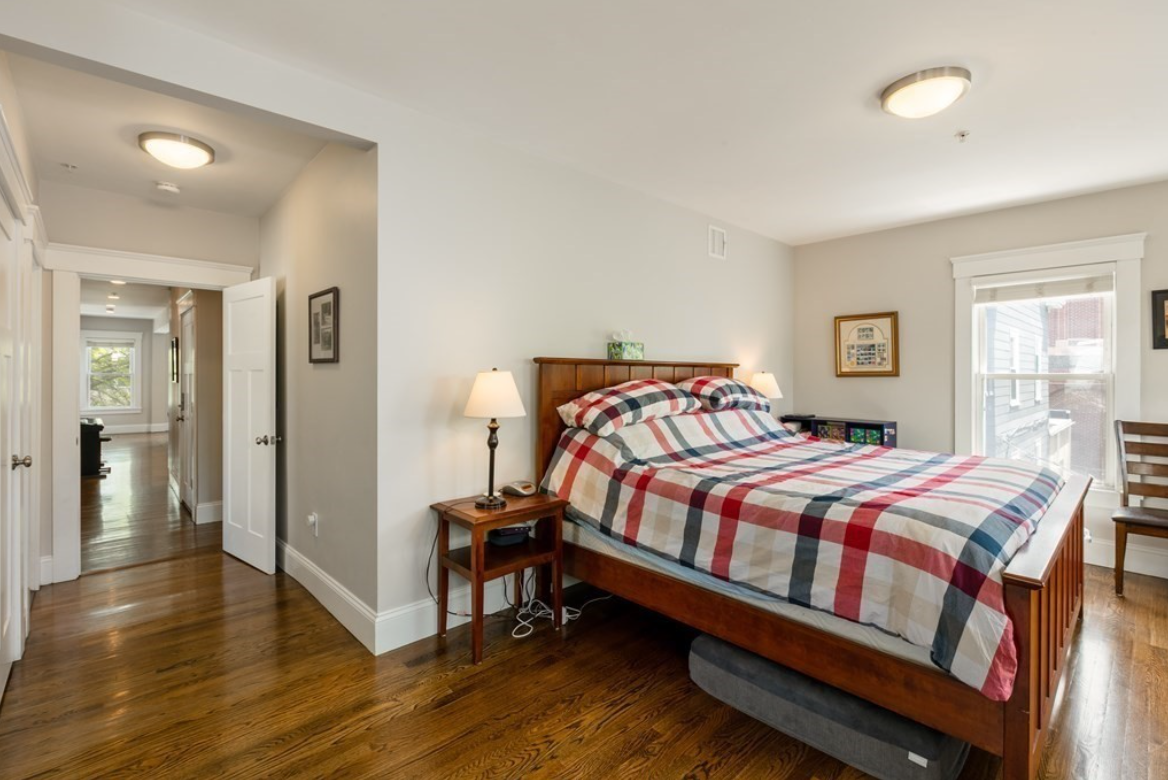 Bedroom with beige walls, hardwood floors, and single-hung window.