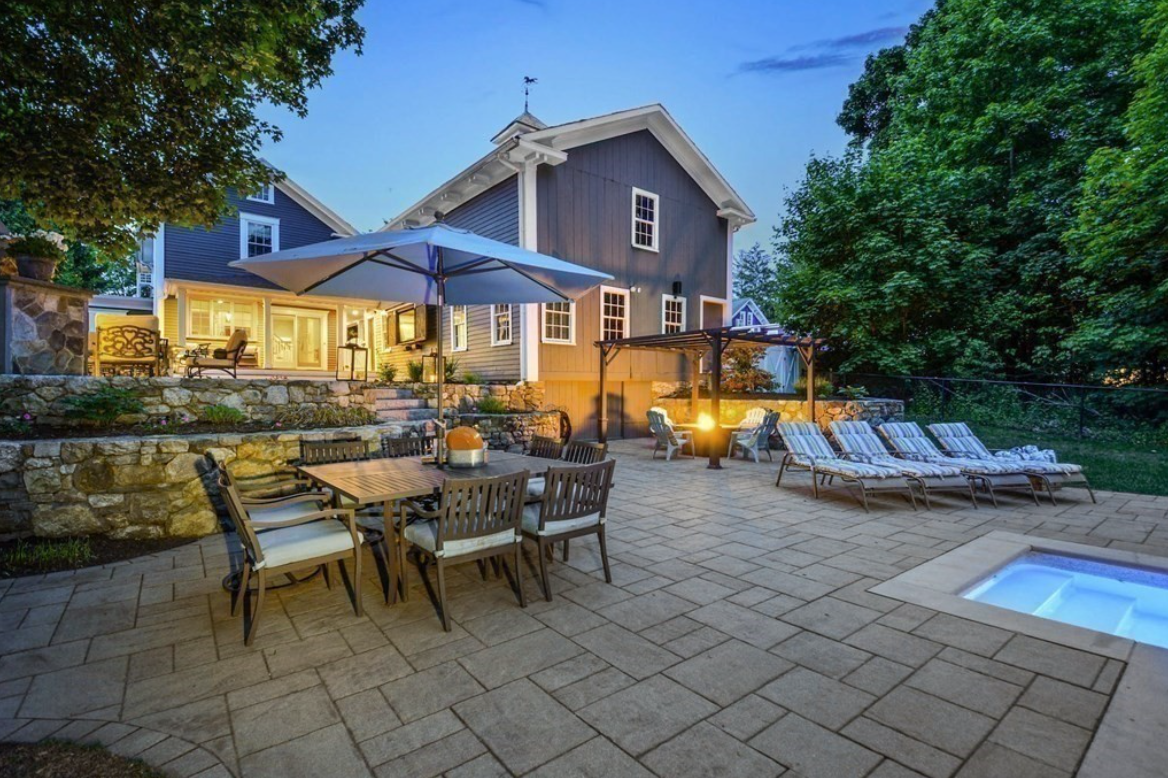 Westborough backyard with in-ground swimming pool, dining table with umbrella, lounge chairs, fire pit, and pergola.