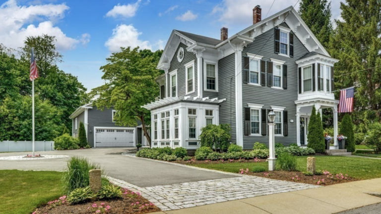 Slate-gray Westborough Colonial with dark shutters, sunroom, and American flag outside.