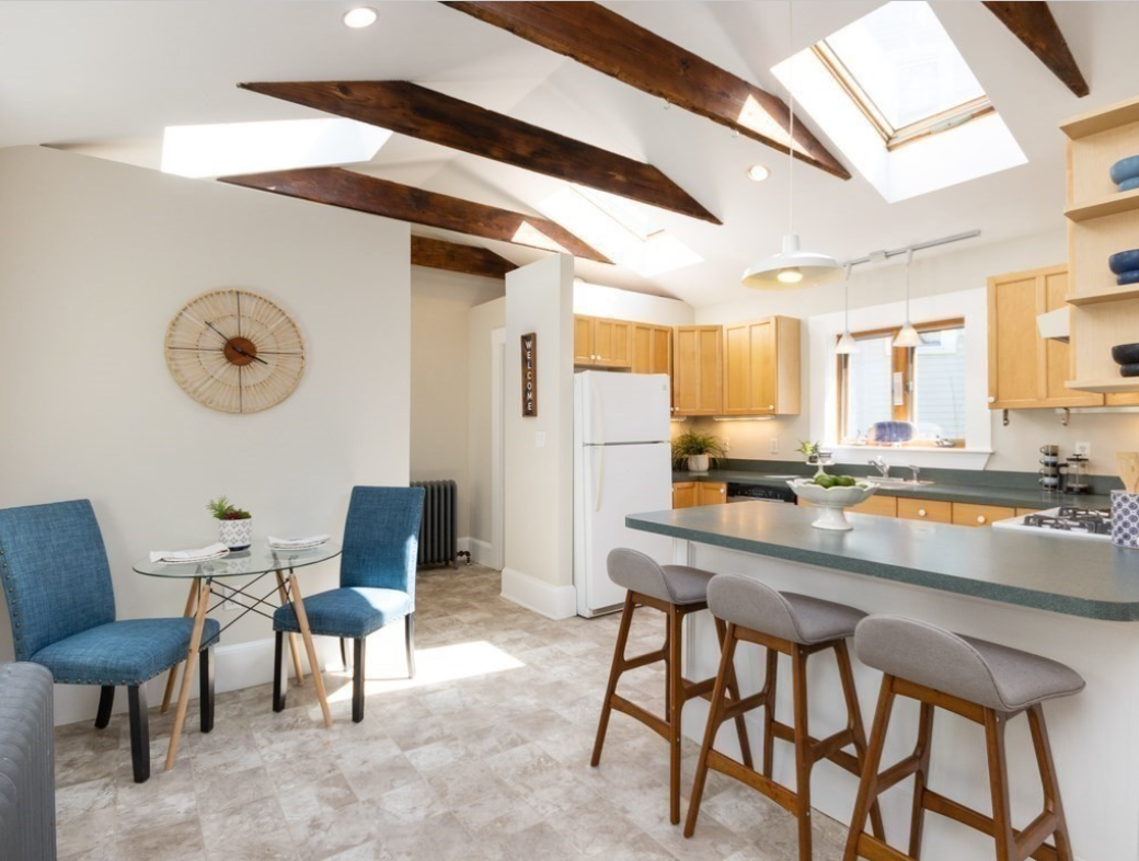 Kitchen with vaulted ceilings, skylights, and exposed wood ceiling beams.