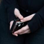 A teenager holds her phone as she sits for a portrait near her home in Illinois.