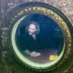 Diving explorer and medical researcher Dr. Joseph Dituri peers out of a large porthole, Saturday, May 13, 2023, at Jules' Undersea Lodge positioned at the bottom of a 30-foot-deep lagoon in Key Largo, Fla.