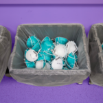 Hospital surgical masks in a garbage can at a hospital seen from above. The background of the image is tinted purple.