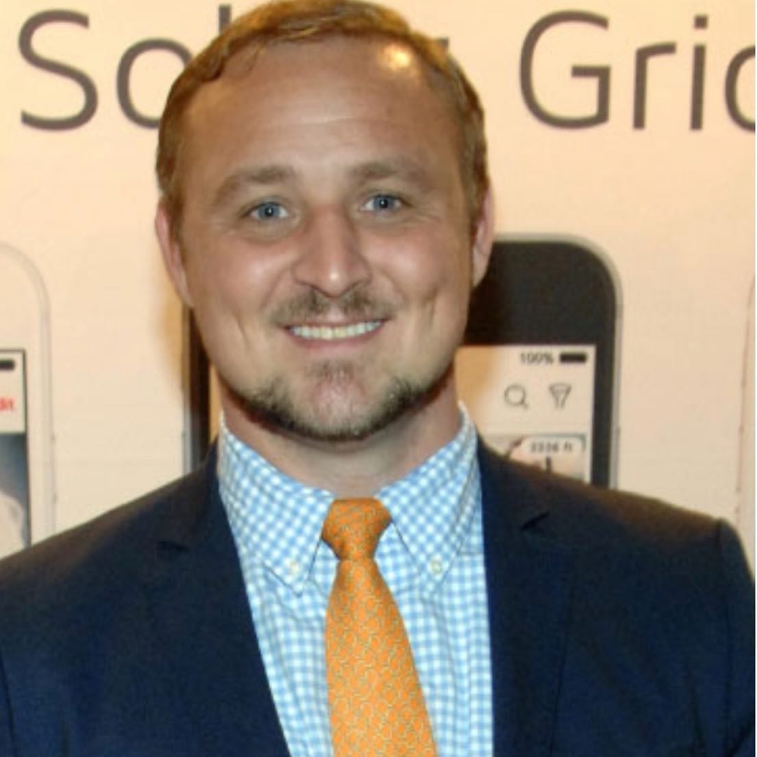 Beau Mann, a 30-something man with short hair and facial hair. He is wearing a suit and smiling at the camera.