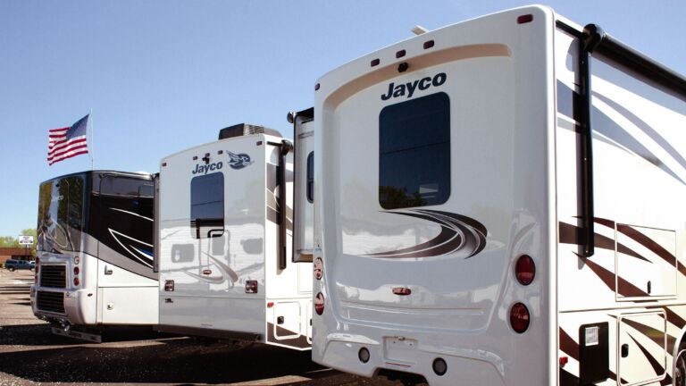 Three large, white campers parked next to each other