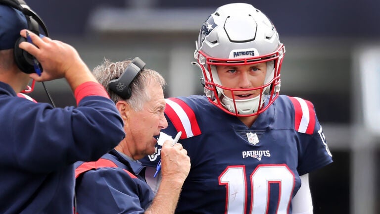 Patriots quarterback Mac Jones (right) listens to head coach Bill Belichick (left) on the sidelines. Joe Judge is at far left. The New England Patriots hosted the Baltimore Ravens in a regular season NFL football game at Gillette Stadium.