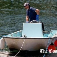 Nate Cunningham, waterfront manager of the Annisquam Yacht Club, uses the club's workskiff, a 1960 Boston Whatler, to move a float in Lobster Cove in Gloucester, Mass.