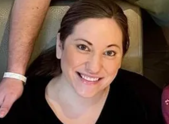 Ariana Sutton is seated, smiling at the camera. She is wearing a black, v-neck shirt and her brown hair is pulled back.