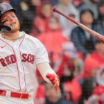 Disgusted batter flips his bat away to the right, with head tilted and eyes closed.