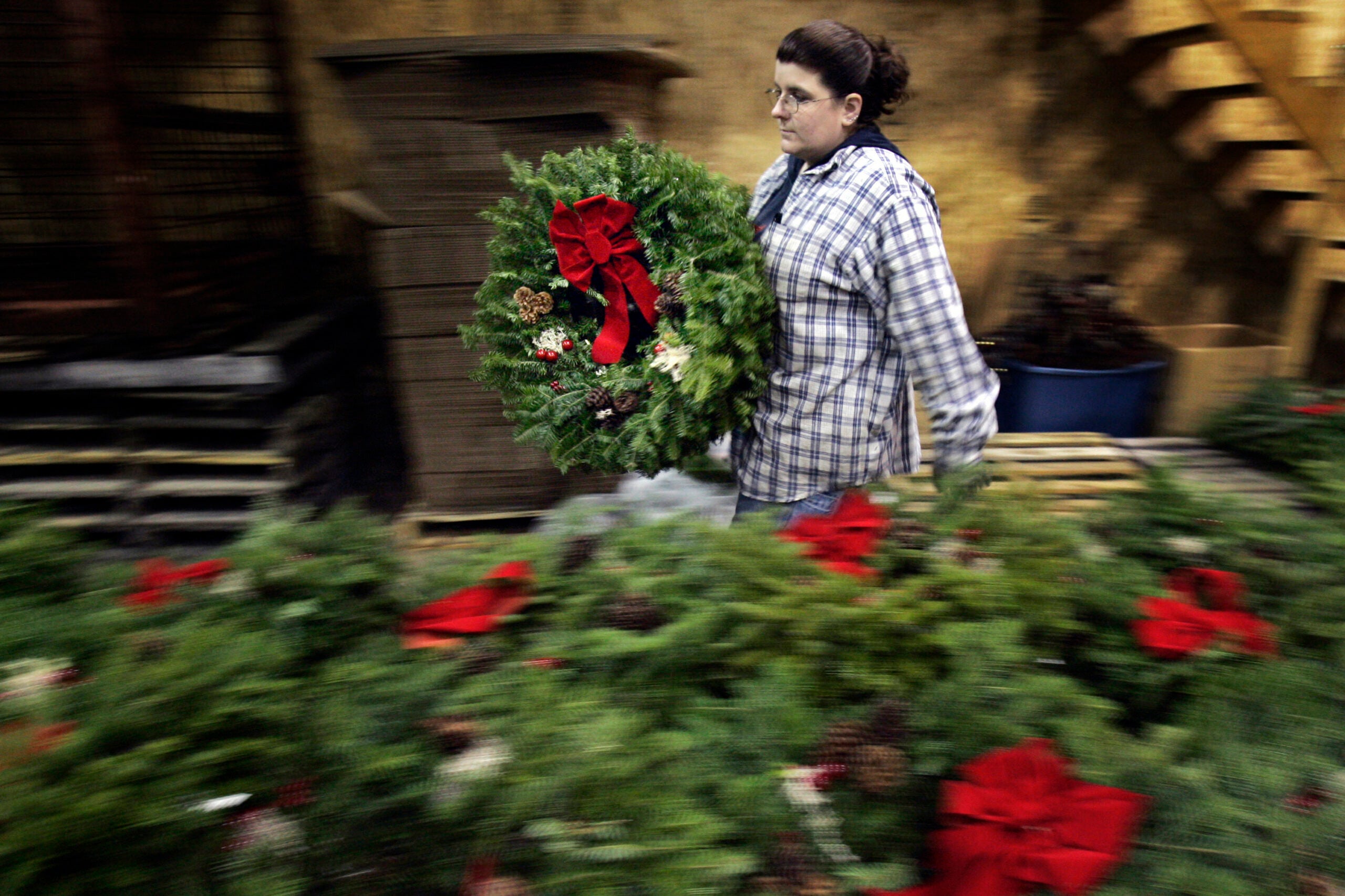 Jill Parritt carries a finished wreath at the Worcester Wreath company in Harrington, Maine.