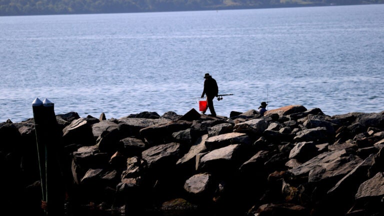 Boston weather -- A fisherman walks a jetty by Quonset Point in North Kingston RI.