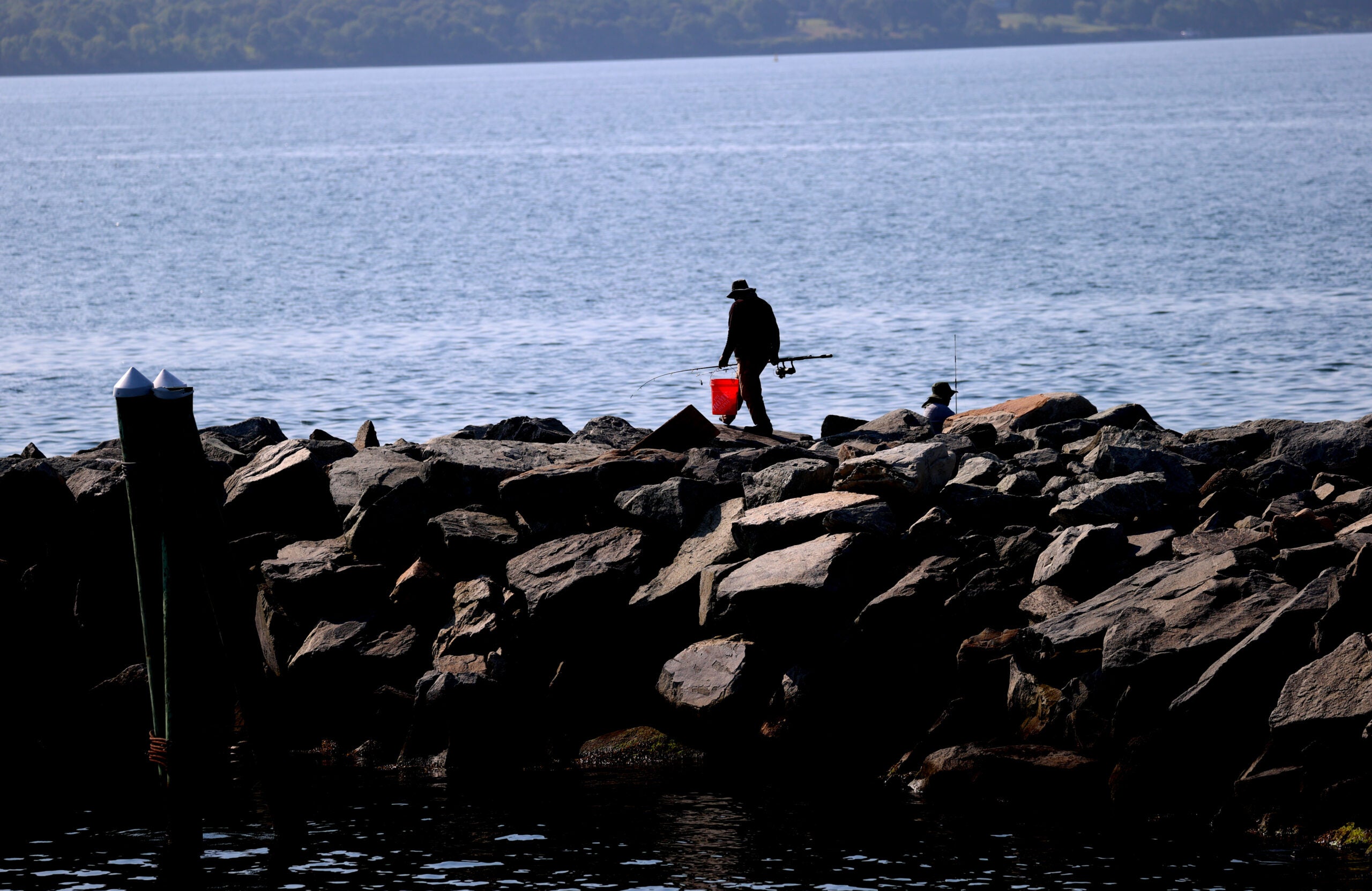 Boston weather -- A fisherman walks a jetty by Quonset Point in North Kingston RI.