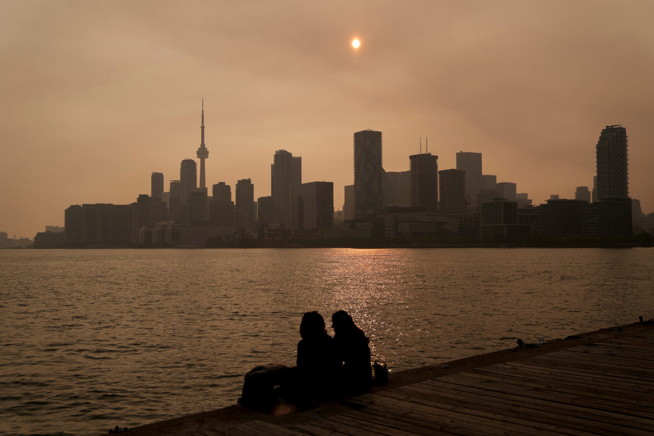 People watch the sunset as the smoke from wildfires is visible in Toronto.