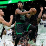 Boston Celtics guard Marcus Smart, center, looks to pass past Washington Wizards center Kristaps Porzingis, left, and forward Rui Hachimura, right, during the first half of an NBA basketball game Oct. 30, 2022, in Boston.