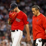 Chris Sale bites his glove as he walks off the field with a trainer.