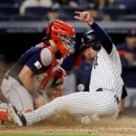 Catcher tries unsuccessfully to catch a baseball as player slides past him.