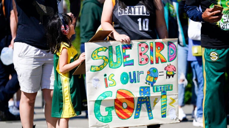 Vicky Chiong, 6, holds a Sue Bird sign with Olivia Chiong as they wait to enter Climate Pledge Arena .