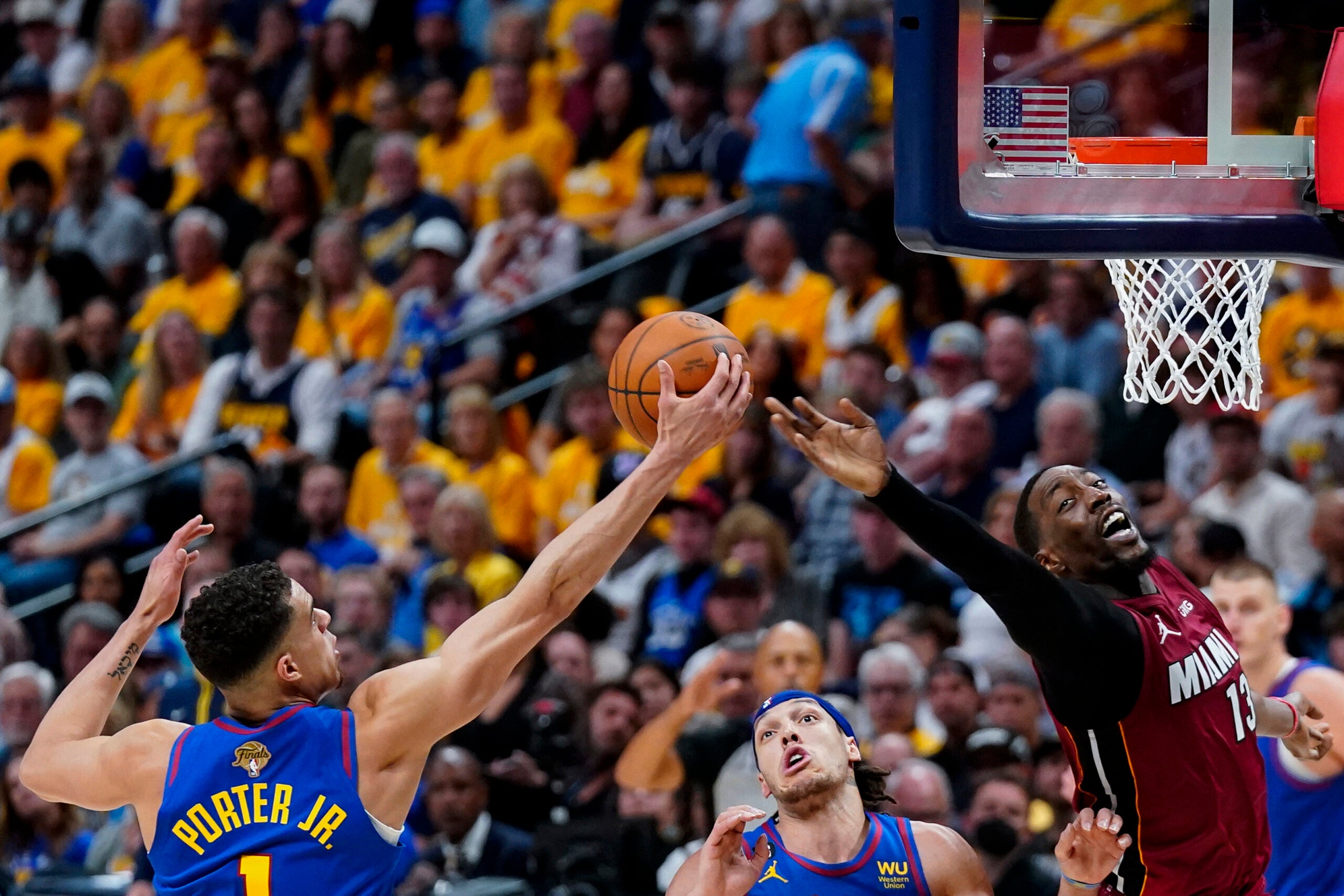 Denver Nuggets forward Michael Porter Jr., left, and Miami Heat center Bam Adebayo reach for the ball during the first half of Game 1 of basketball's NBA Finals.