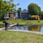 Three yellow inflatable tube men overlook a pond
