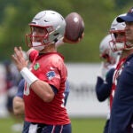 New England Patriots quarterback Mac Jones, left, winds up to pass in front of offensive coordinator Bill O'Brien, right, during an NFL football team practice, Tuesday, June 13, 2023, in Foxborough, Mass.