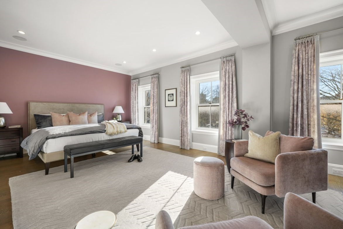 Primary bedroom with mauve accent wall and single-hung windows, hardwood floors, and white crown moulding.