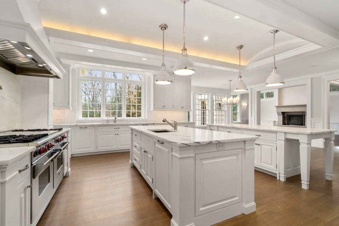 Kitchen with white walls and white cabinetry, hardwood floors, pendant lighting, and picture windows with muntins.