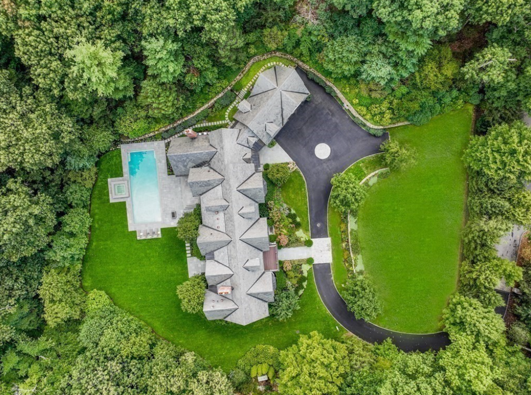 Aerial view of estate with in-ground swimming pool and winding driveway.