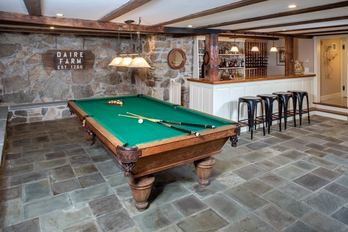 Basement with stone floors, wet bar, and exposed wood ceiling beams.