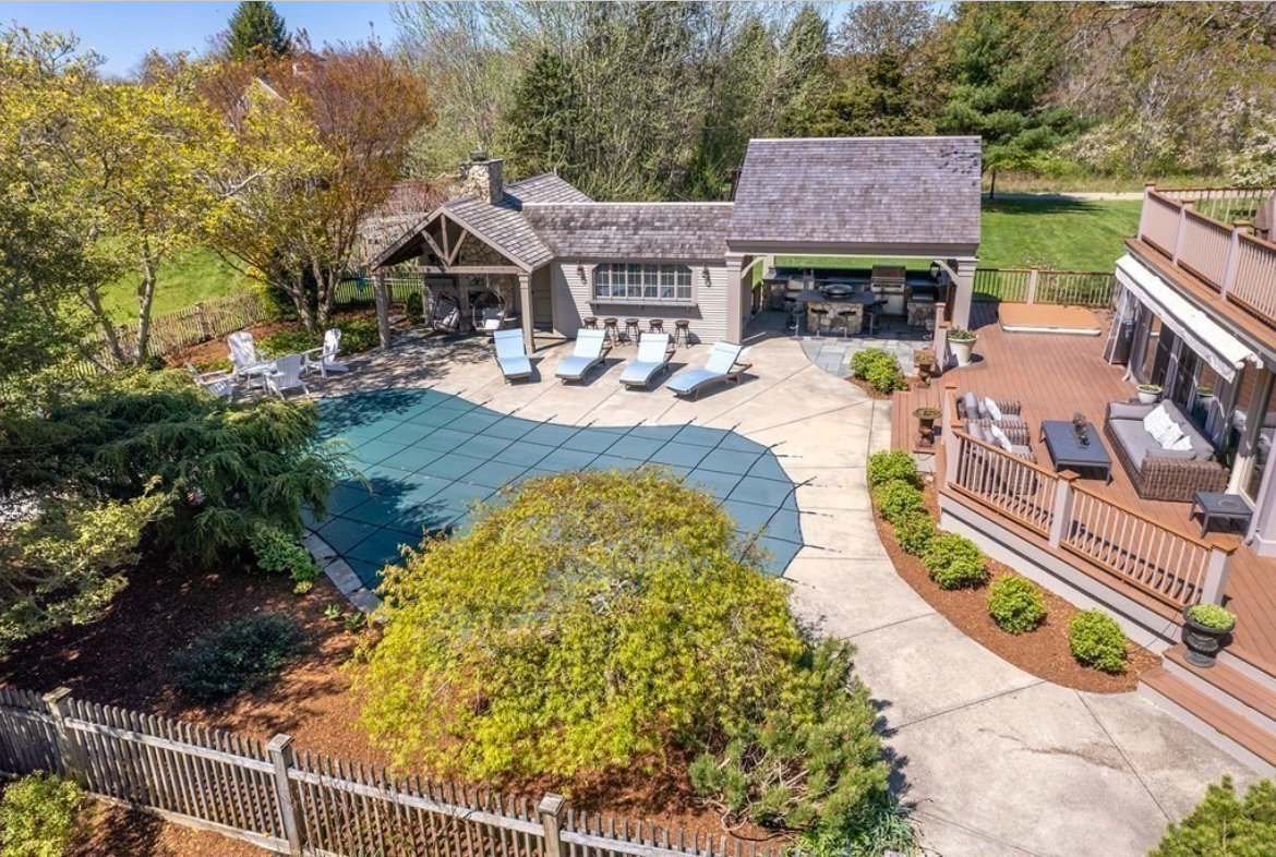 Backyard with in-ground swimming pool, covered kitchen with grill, deck, and pool shed.