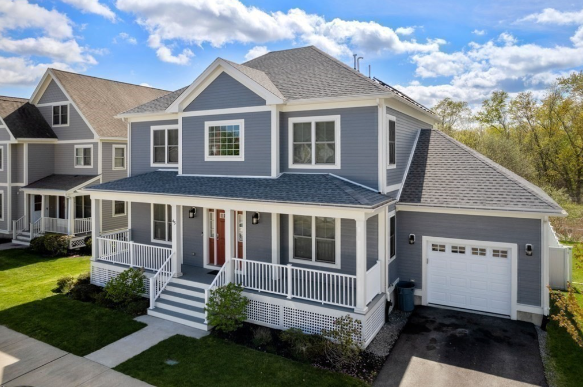 Slate-blue Colonial with white trim and wraparound porch.